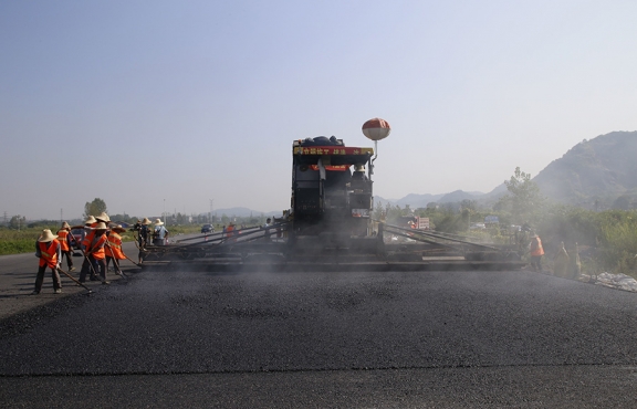 2019年8月，宜春經開區(qū)S311路面攤鋪現場，工友們輔助路面兩側的分料、補窩等作業(yè)